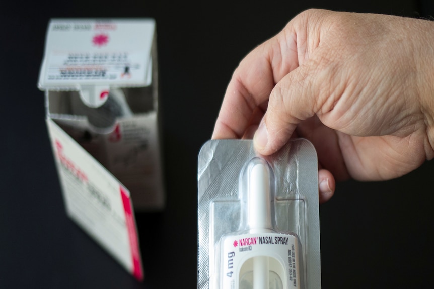 A pair of hands holding a nasal spray box 