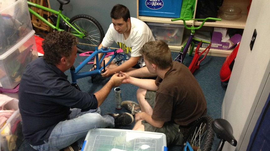 Volunteer James Kemp helping participants rebuild old bicycles as part of the Two Wheels program