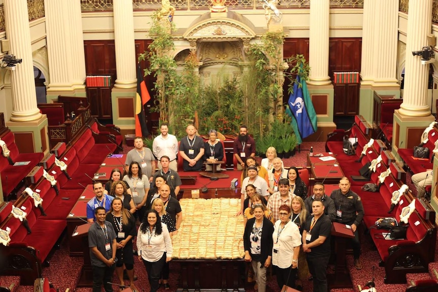 The First Peoples' Assembly members gather around a possum quilt inside the Parliament's Upper House.