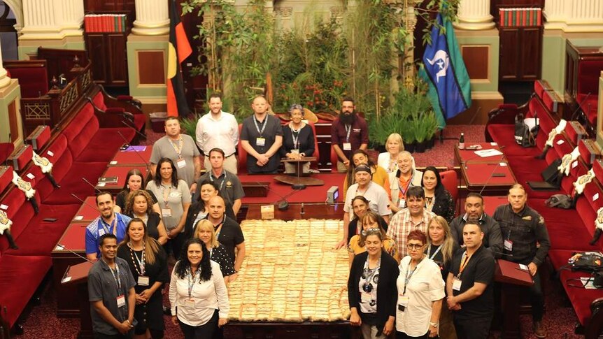 The First Peoples' Assembly members gather around a possum quilt inside the Parliament's Upper House.