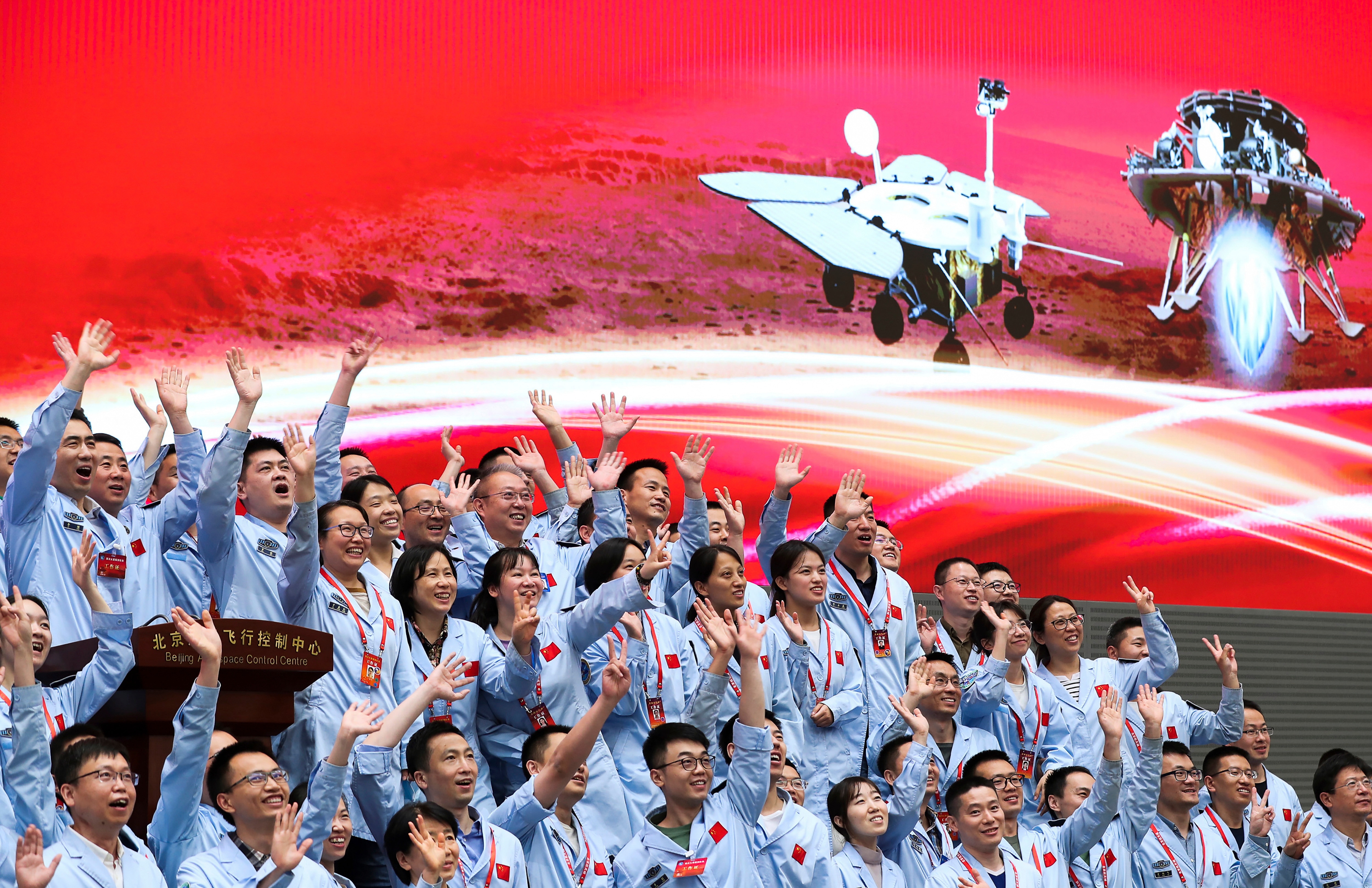 A crowd of people at the Beijing Aerospace Center throw their hands in the air and shout after a Mars landing.