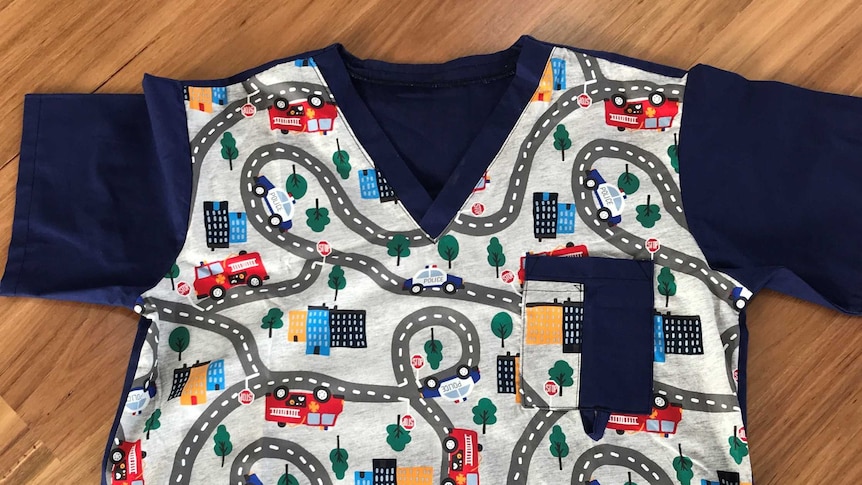 A scrubs top worn by medical professionals made of colourful fabric featuring cars.