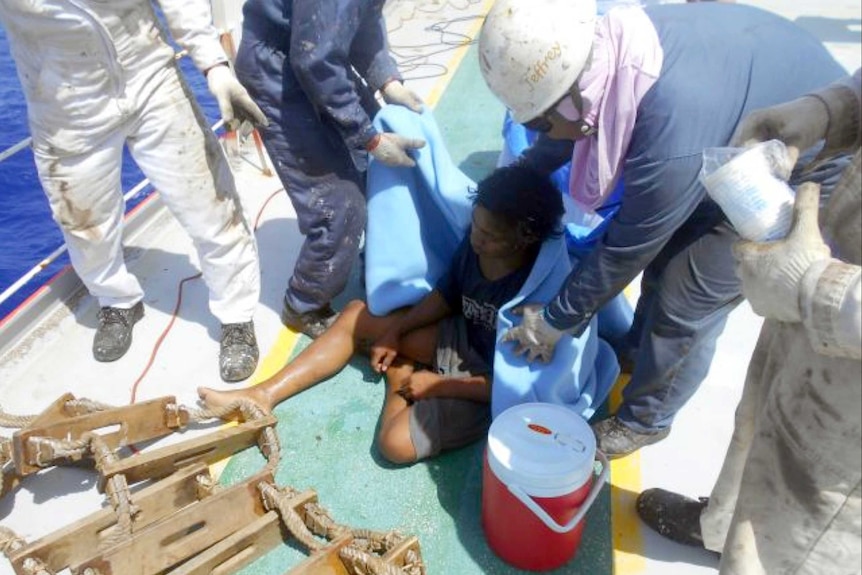 Aldi Novel Adilang sits on the deck of a ship after being rescued.