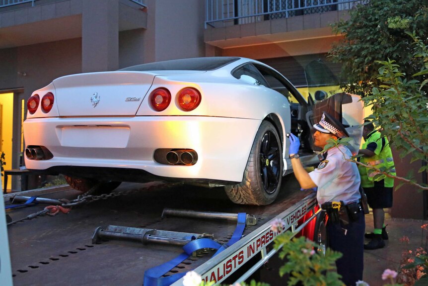 Police inspect a Ferrari