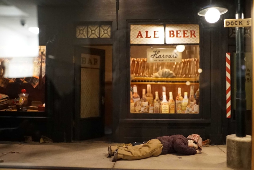 A tiny crime scene model - man lying face down in front of a pub.
