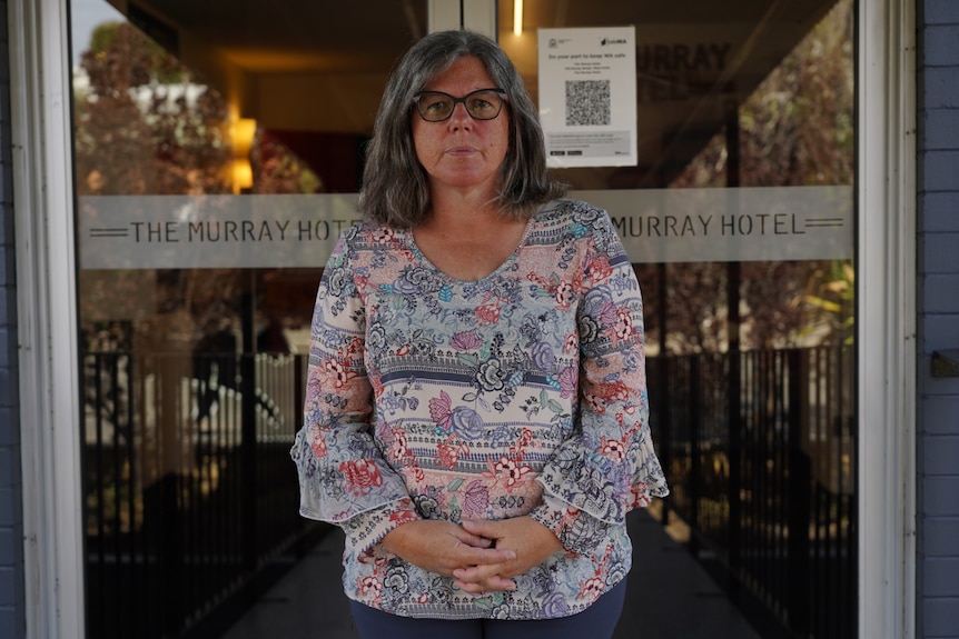 The Murray Hotel owner Kate Sinfield standing in front of the doors to her hotel with a serious expression