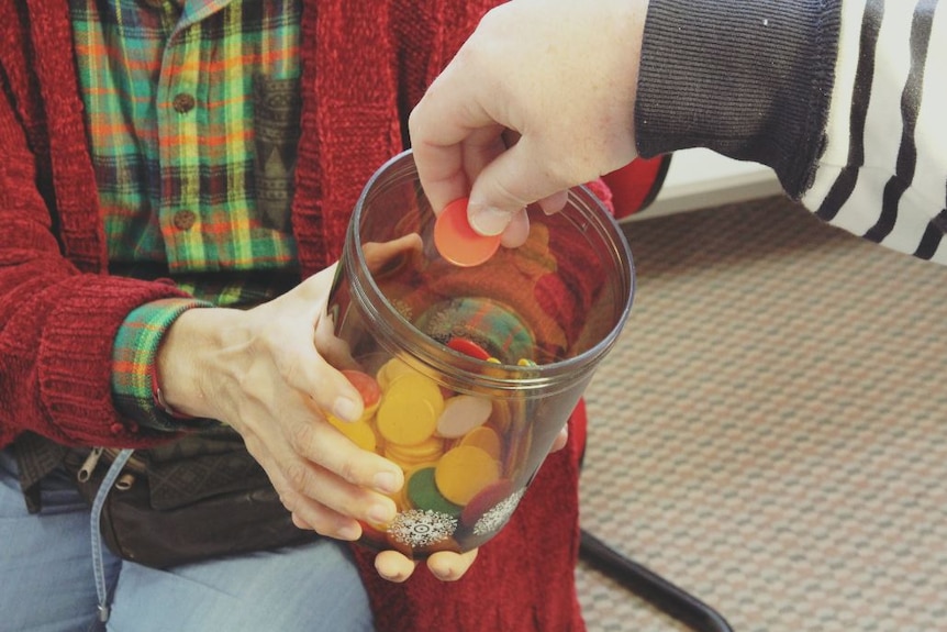 A hand selecting a coloured disc out of a lucky dip container