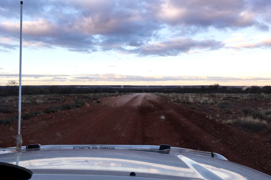 a photo of dark clouds and a dirt road