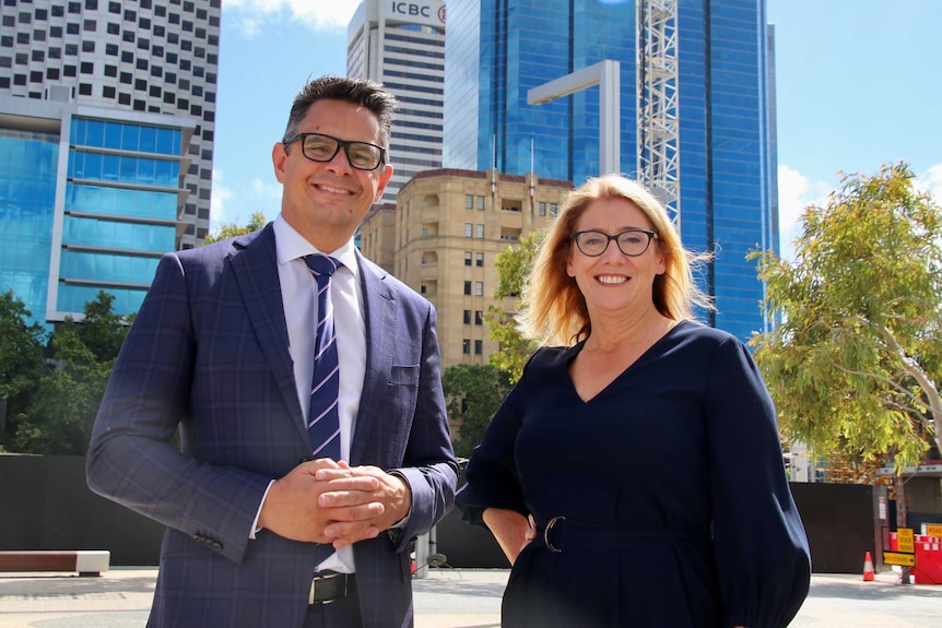 A mid shot of a smiling Ben Wyatt and Rita Saffioti standing side by side smiling for the camera in front of CBD buildings.