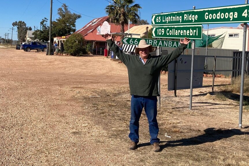 Man under road sign in Hebel south west Queensland