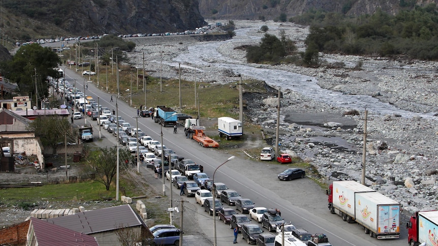 aerial shot of hundreds of cars queues, snaking along narrow four lane coutry road