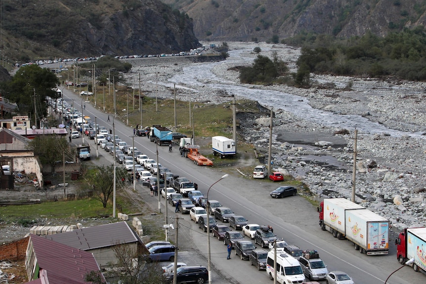 aerial shot of hundreds of cars queues, snaking along narrow four lane coutry road