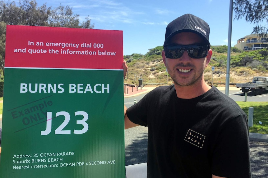 Rick Gerring standing alongside one of the signs that will help guide emergency services to the scene of a shark attack.