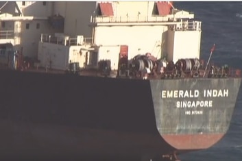 The back of a container ship on which the words Emerald Indah Singapore are printed.