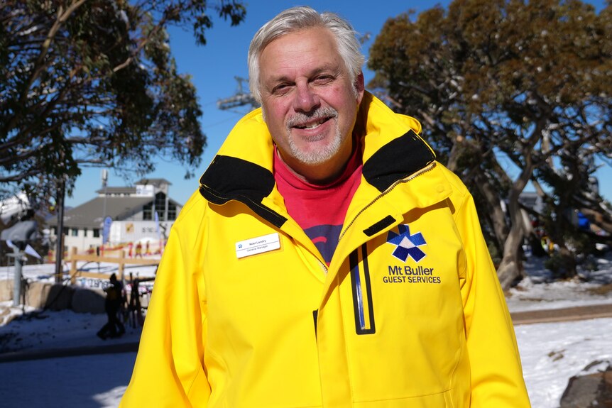 Man in a bright yellow ski jacket smiles. 
