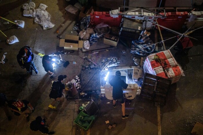 A group of protesters, surrounded by equipment, shine a strong light down a manhole