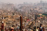 A charred scene of burnt out villages as people rake over the smoldering wreckage.