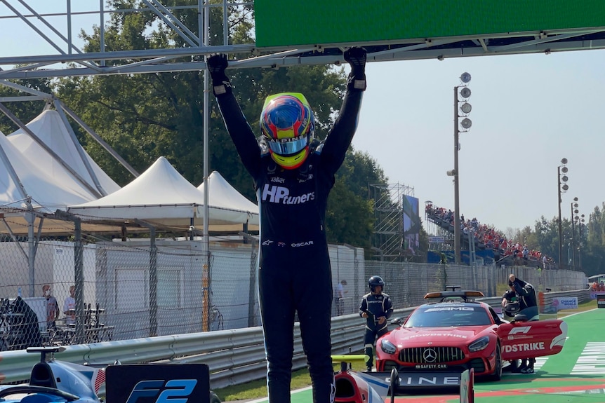 Racing driver standing on his car celebrating.