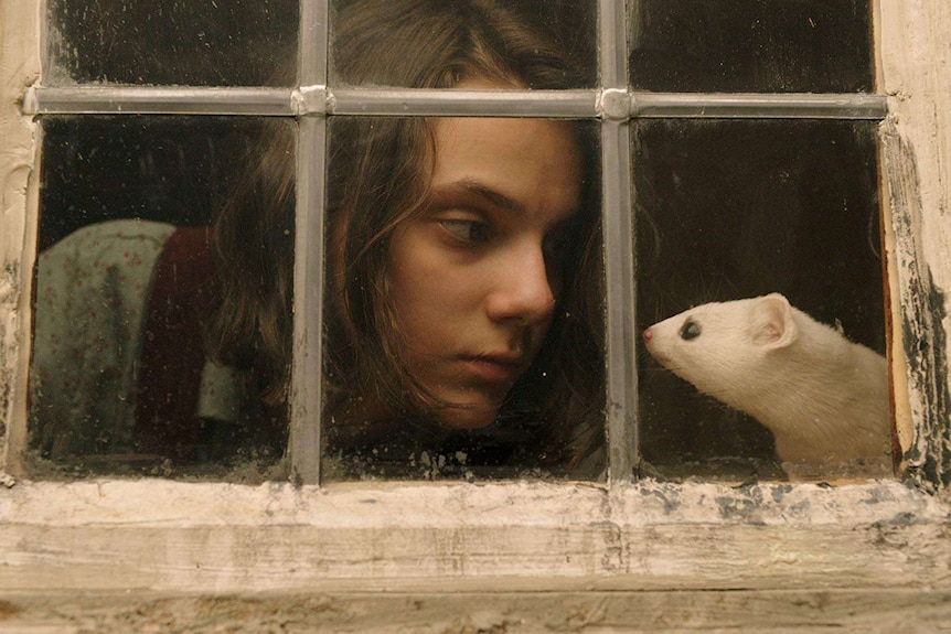 A girl stares into the face of an ermine