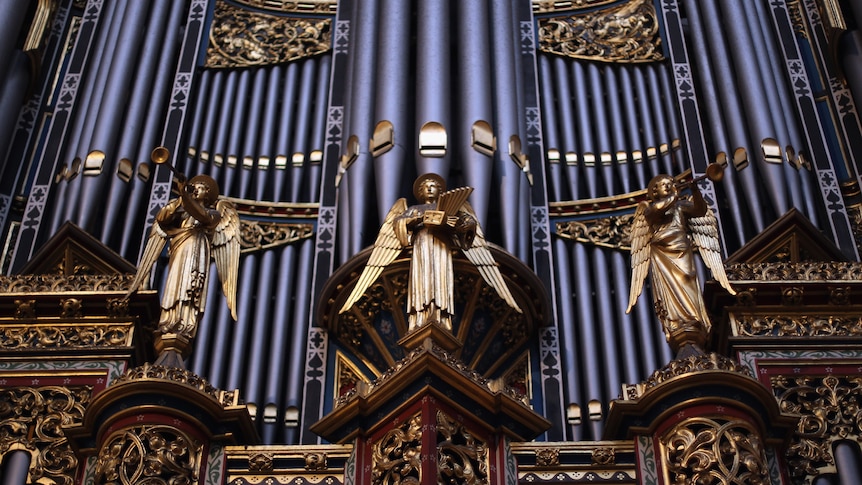 The organ pipes at Westminster Abbey with gold ornamentation of heralding angels and filigree