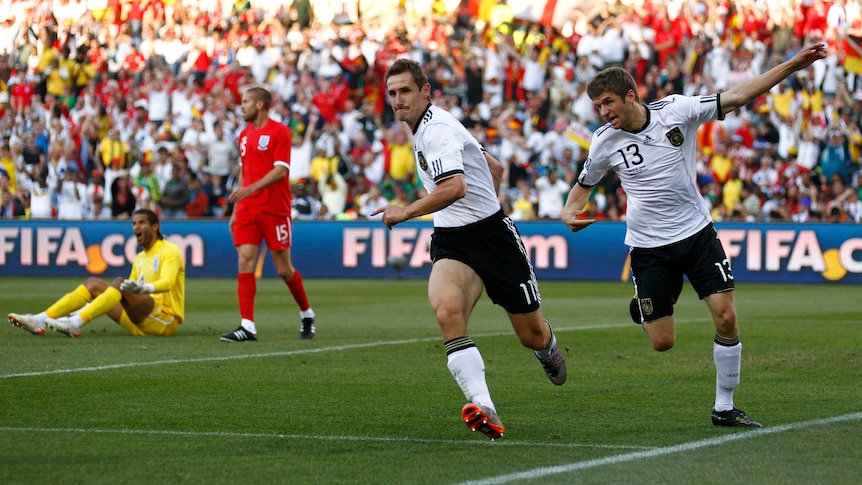 Two German forwards run away from goal after scoring in a World Cup match against England. 