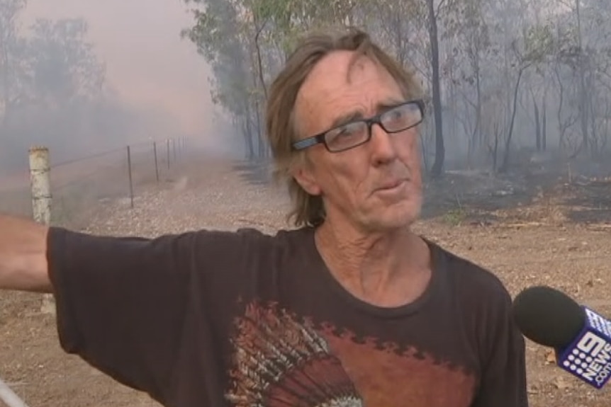 Herbie Brearley wears a brown t-shirt and speaks into an ABC microphone