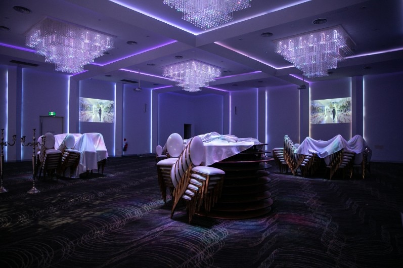 A bunch of empty tables and chairs at a wedding reception venue.