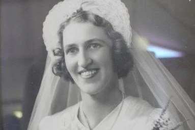 A black-and-white shot of a smiling young woman in a wedding veil.