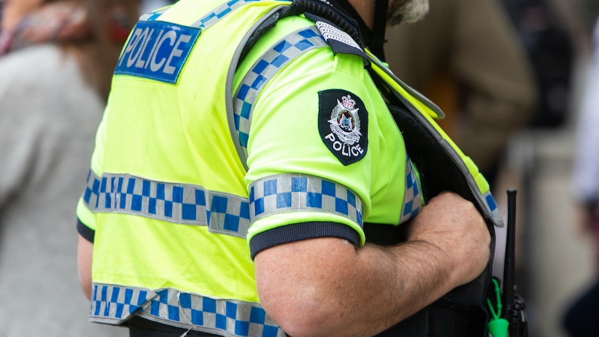 A photo of the torso of a police officer wearing a high vis vest.