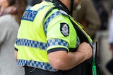 A photo of the torso of a police officer wearing a high vis vest.