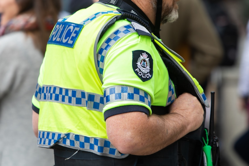 A photo of the torso of a police officer wearing a high vis vest.