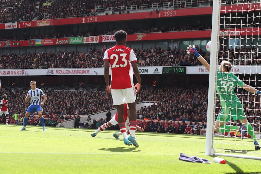 A Premier League footballer stands on the edge of the box watching his shot fly past a defender and goalkeeper into the net. 