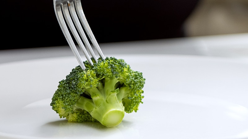 A fork on a piece of broccoli on a plate
