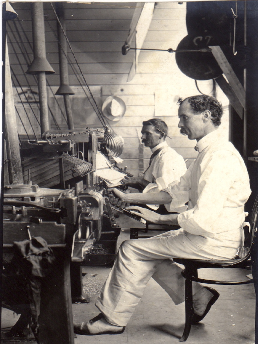 Black and white photo of two journalists using old machinery at The Evening Telegraph.