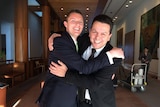 Sam Johnson and Nick Xenophon smile as they embrace.