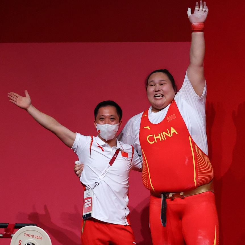 Coach Wu Meijin (left) embraces with Chinese weightlifter Li Wenwen (right).