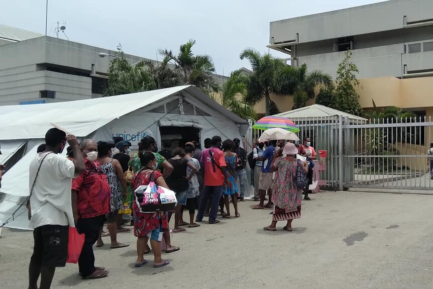 People queue outside a hospital.