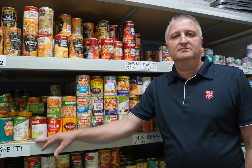 Man stands in front of cans of food