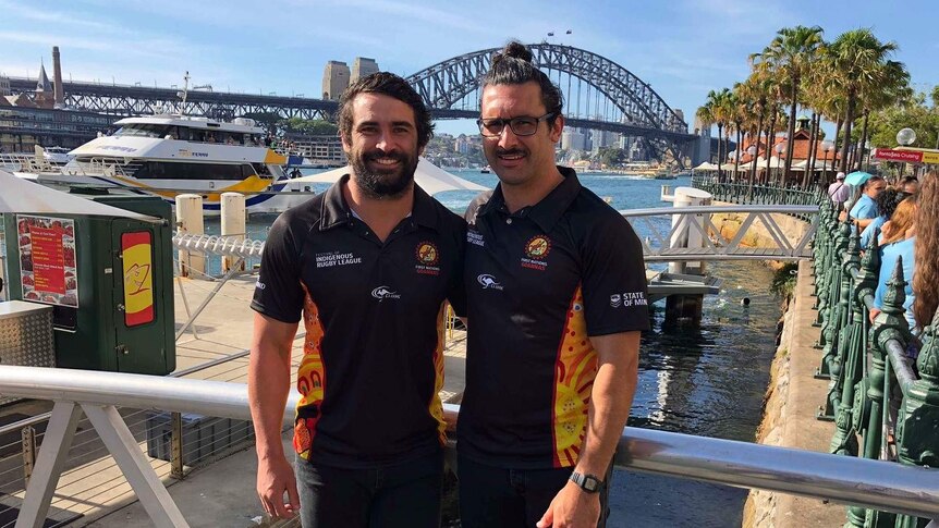 Two men pose in front of the Harbour Bridge