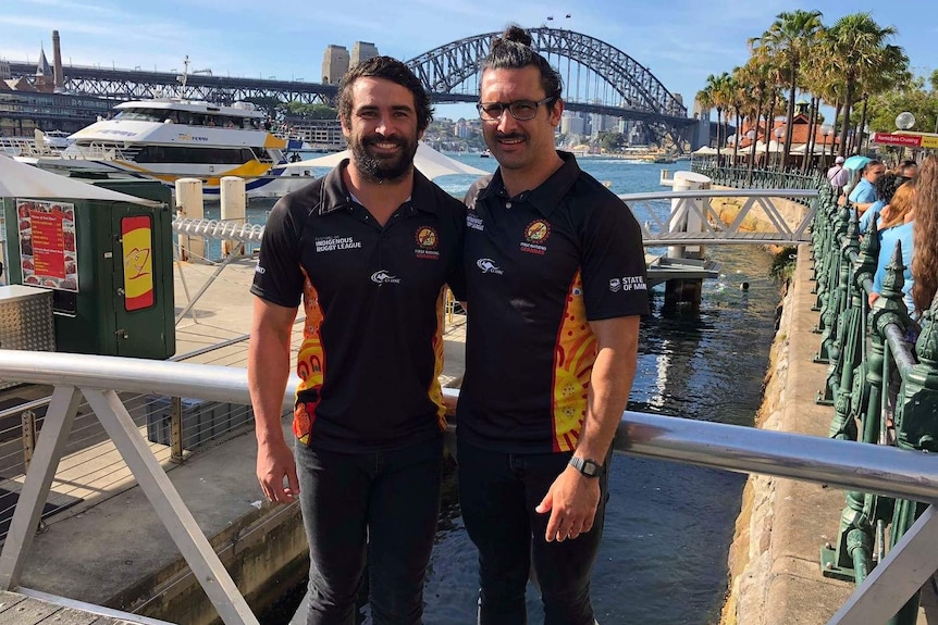 Two men pose in front of the Harbour Bridge