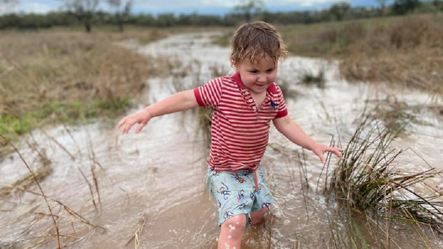 A young boy plays in water on a rural property