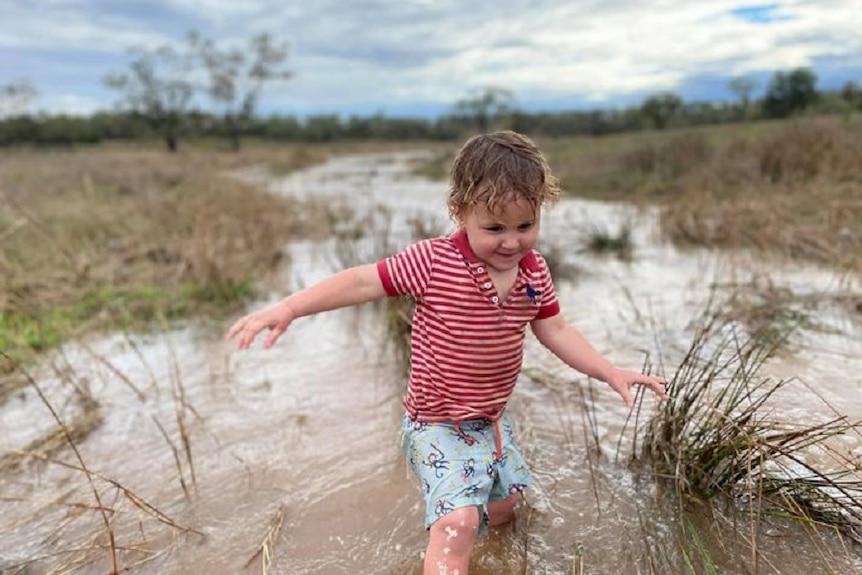 A young boy plays in water on a rural property