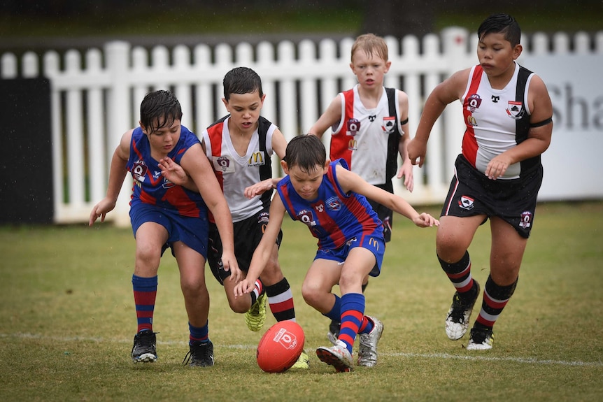 Children playing Aussie rules in the rain.