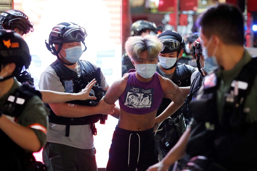 A man wearing a crop top is arrested by Hong Kong police officers.