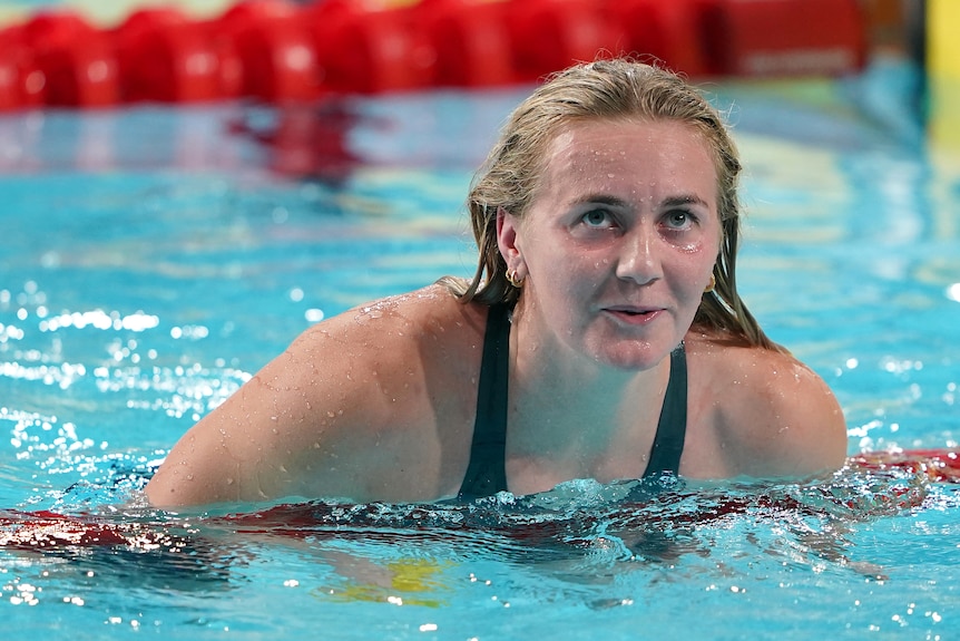 Ariarne Titmus smiles rolling over the lane rope