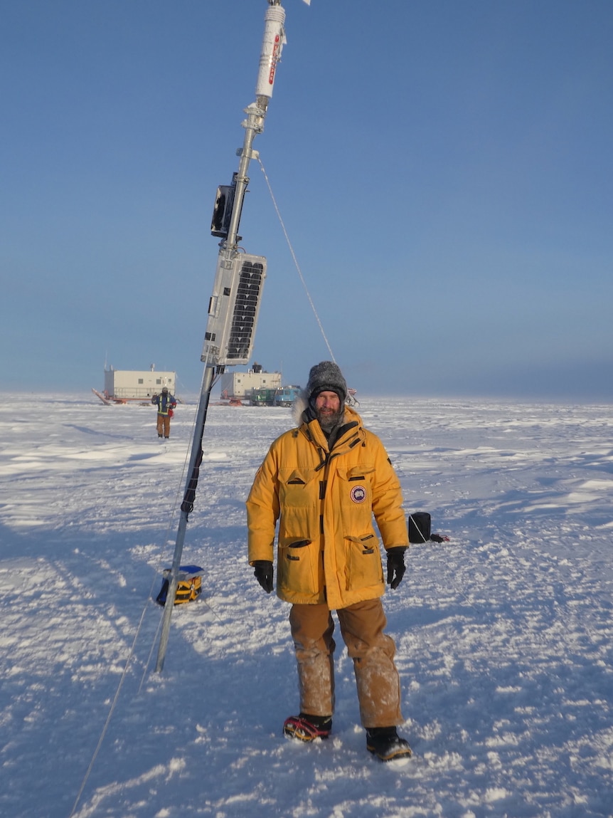 Picture of a man in a yellow coat standing next to a weather station