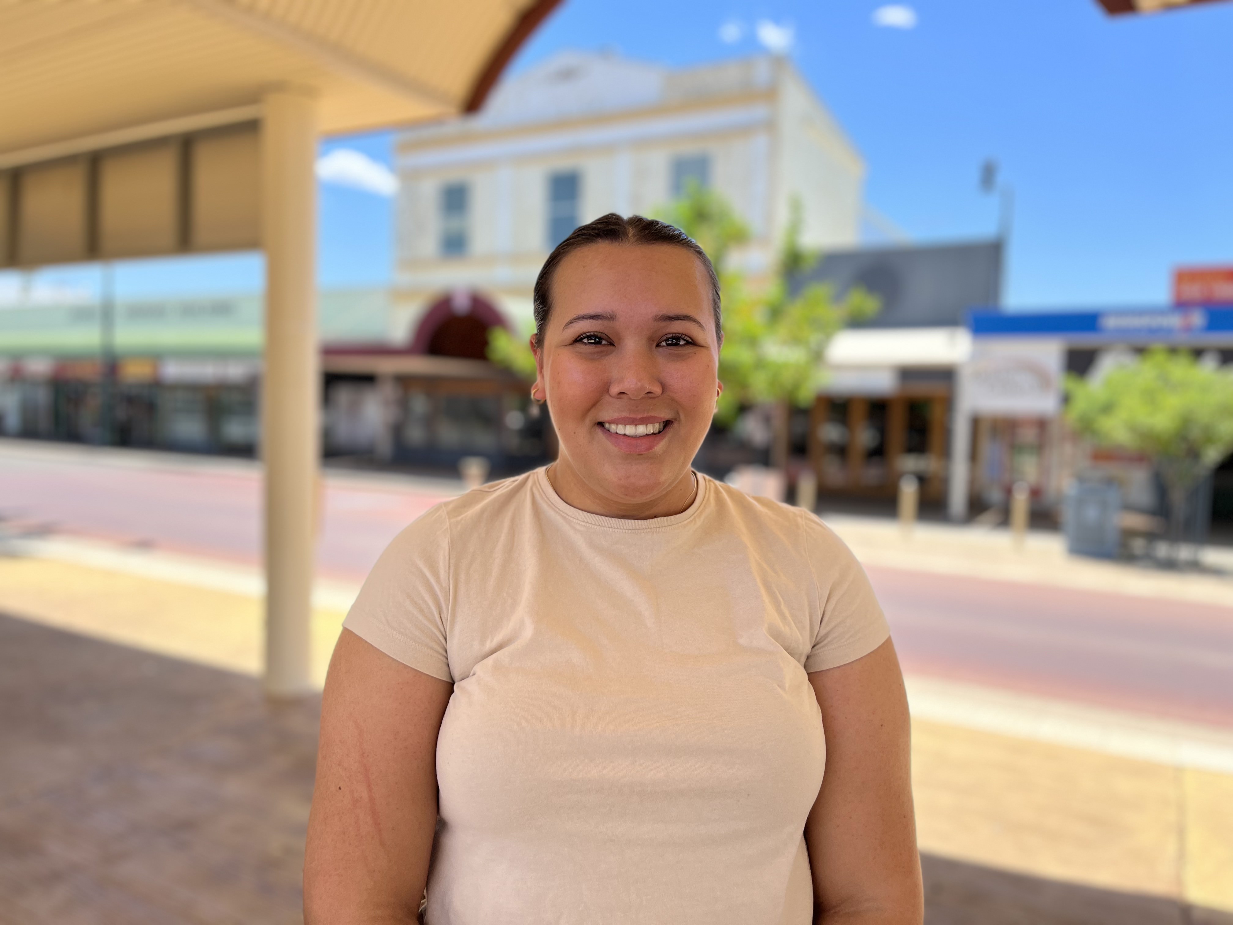 Girl standing under shade in midday in middle of street