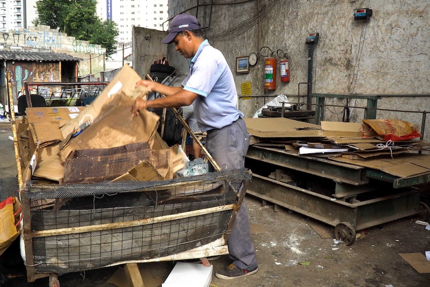 A person sorts through cardboard on a wagon.