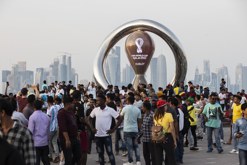 A number of people outside near a structure that says Qatar World Cup 2022