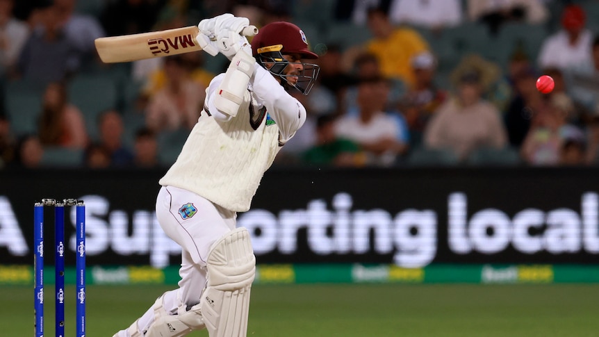 A West Indies batsman watches as he completes his follow-through from a shot and the ball flies away to the boundary.